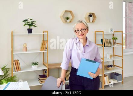 Porträt einer selbstbewussten und freundlichen Geschäftsfrau, die in ihrem gemütlichen Büro steht. Stockfoto