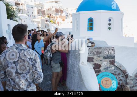 Oia, Griechenland - 9 2022. September: Enge, überfüllte und gezahnte Straßen in Oia, Santorini, gefüllt mit einer Menge Touristen mit Smartphone-Fotos Stockfoto