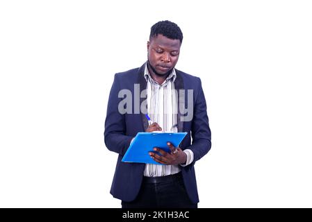 Junger ernsthafter Geschäftsmann, der einen eleganten Anzug trägt und mit einem Stift auf die Zwischenablage schreibt. Stockfoto