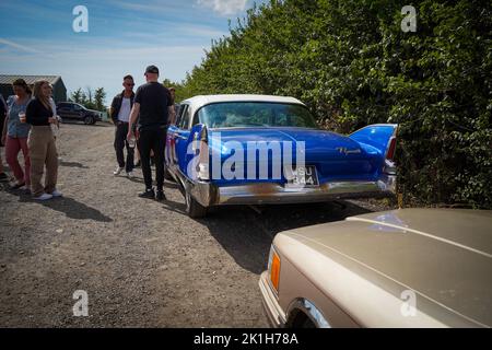 Exeter, UK-August 2022: Besucher einer Oldtimer-Show auf der Greendale Farm bei Exeter mit einem 1960 Plymouth im Vordergrund Stockfoto