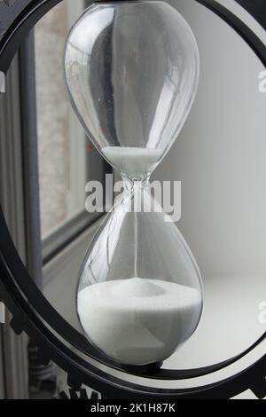 Nahaufnahme einer Sanduhr mit Sand aus dem oberen Teil. Termin. Stockfoto