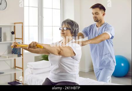 Erfahrener männlicher Physiotherapeut, der mit älteren Patienten im Rehabilitationszentrum arbeitet Stockfoto