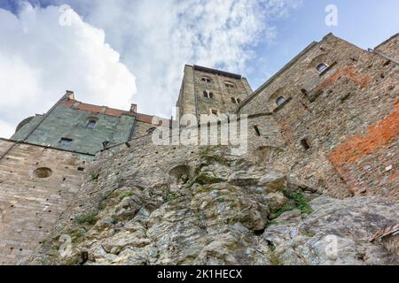 Die imposanten Mauern, die aus den Felsen der mittelalterlichen Abtei Sacra di San Michele im Susatal, Italien, zu wachsen scheinen Stockfoto