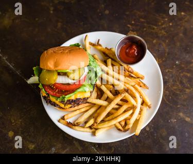 Cheeseburger mit zwei Patties, Gurken und pommes Frites an einer Bar Stockfoto