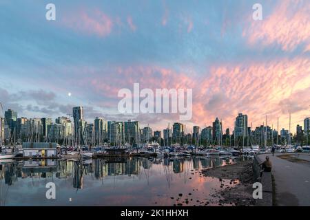 Frau, die einen atemberaubenden Sonnenuntergang über Vancouver, Kanada, mit einem Spiegelblick auf den Hafen vom Stanley Park aus beobachtet. Stockfoto