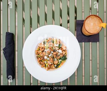 Sautierte Hähnchenspeise mit Feta-Käse und in einer weißen Servierschüssel mit sautiertem Spinat Stockfoto