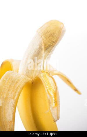 Eine halb geschälte Banane mit Honig oder Sirup, der heruntertropft. Stockfoto