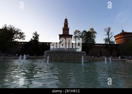 Mailand, Italien - 18. September 2022: Dämmerung auf der Piazza Castello wird der blaue Himmel dunkel über dem in Gold beleuchteten Castello Sforzesco. Stockfoto