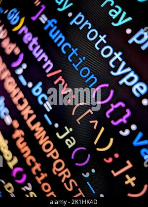 Nahaufnahme von Computercode-Zeilen, die auf einem digitalen Bildschirm mit farbigen Buchstaben und Zahlen im dunklen Modus auf schwarzem Hintergrund angezeigt werden Stockfoto