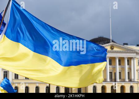 Helsinki, Finnland - 26. März 2022: Ukrainische Flaggen mit dem finnischen Regierungspalast im Hintergrund bei einer Kundgebung gegen den russischen Militärs Stockfoto