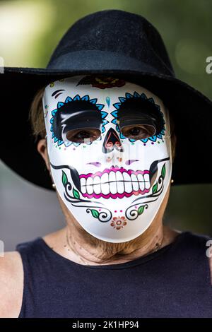 Porträt einer älteren Dame mit catrina-Maske und Hut, die Halloween und All Souls' Day feiert, auf der Straße. Feier, Kostüm, Party und Maske Stockfoto