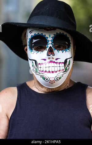 Porträt einer älteren Dame mit catrina-Maske und Hut, die Halloween und All Souls' Day feiert, auf der Straße. Feier, Kostüm, Party und Maske Stockfoto