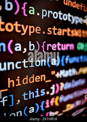 Computercode, der auf einem verpixelten Bildschirm mit farbigen Zeichen auf einem dunklen Hintergrund angezeigt wird Stockfoto