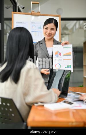 Portrait, erfolgreiche und professionelle, tausendjährige asiatische Chefin oder CEO leiten das Meeting, erklären und coachen ihrem Team etwas. Stockfoto