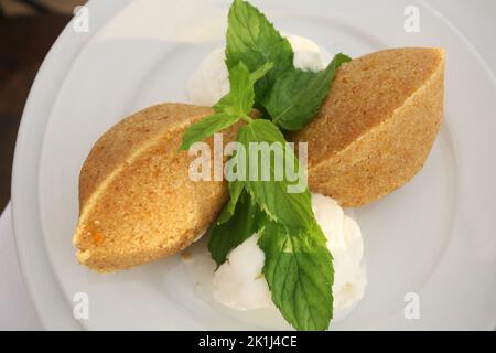 Traditionelles türkisches Dessertgrieß Halva (türkisch: Irmik helvasi) mit Eis auf dem Dessertteller. Stockfoto