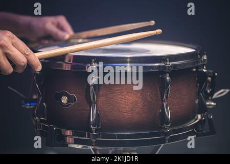 Schlagzeuger, der Schlagzeug spielt, hängt auf einer Snare-Trommel auf schwarzem Hintergrund. Stockfoto