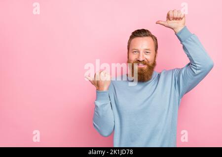 Foto von gutaussehenden guten Laune Kerl mit Ingwer-Bart gekleidet blau lange Ärmel zeigt leeren Raum isoliert auf rosa Hintergrund Stockfoto