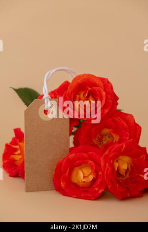 Einfarbige beige Papiernote und Seil in Herzform auf neutralem beigen Hintergrund. Zarte rote Rosen Grußkarte Feiertagsidee. Erstellen Sie einen Kopierplatz für Text. Geschenk Stockfoto