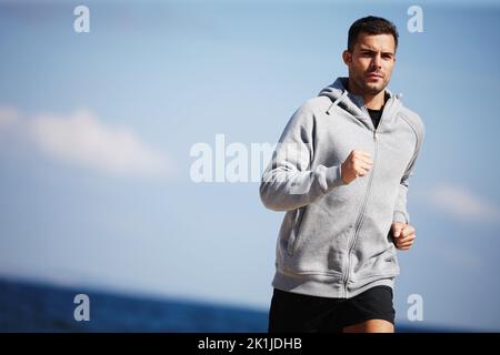 Joggen in der Nähe des Meeres. Ein hübscher junger Mann, der am Strand läuft. Stockfoto