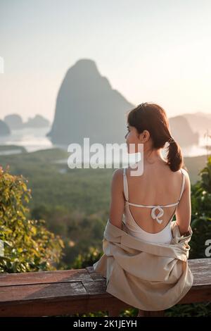 Glückliche Reisende Frau genießen Phang Nga Bucht Aussichtspunkt, allein Touristen sitzen und entspannen in Samet Nang She, in der Nähe von Phuket in Südthailand. Südosten Stockfoto