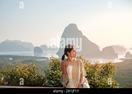 Glückliche Reisende Frau genießen Phang Nga Bucht Aussichtspunkt, allein Touristen sitzen und entspannen in Samet Nang She, in der Nähe von Phuket in Südthailand. Südosten Stockfoto