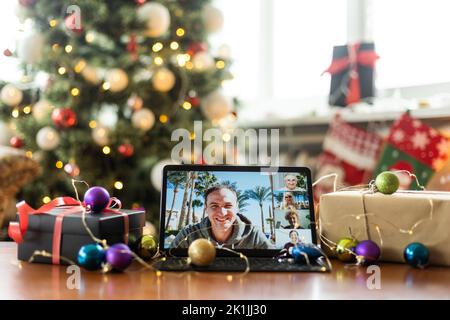 Große Familie singt weihnachtslied auf Tablet-Kamera während Online-Videoanruf. Lächelnde Eltern und Kinder. Fröhliche Familie gratuliert Verwandten mit Stockfoto