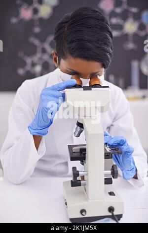Sorgfältige Analyse und Beobachtung. Eine junge Wissenschaftlerin, die in ihrem Labor ein Mikroskop benutzt. Stockfoto