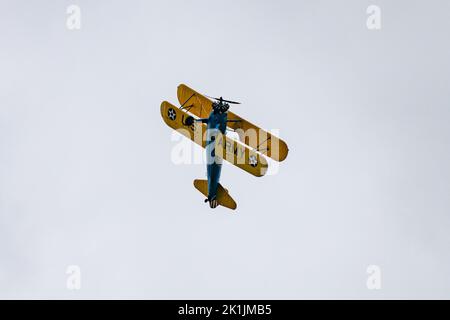 Die Low-Angle-Ansicht eines alten Doppelflugzeugs der US Navy, das Kunstflug am grauen Himmel durchführt Stockfoto