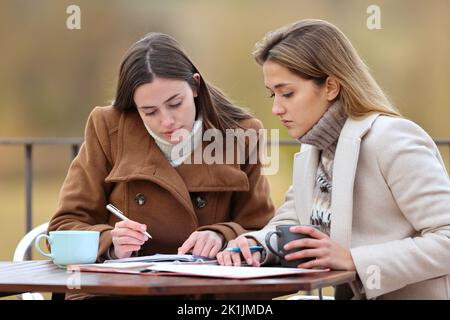 Zwei Studenten überprüfen im Winter auf einer Terrasse Papiernoten Stockfoto