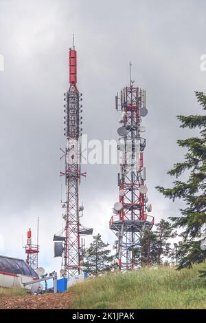 Telekommunikationsturm und Mobilfunksignalrepeater auf der Bergspitze am bewölkten Tag Stockfoto