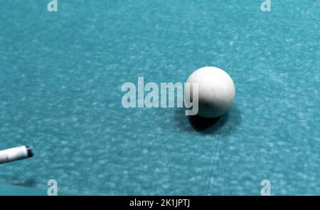 Cue-Ball auf einem abgenutzten alten Billardtisch. Eine Partie Billard mit gebrauchter Ausrüstung. Stockfoto