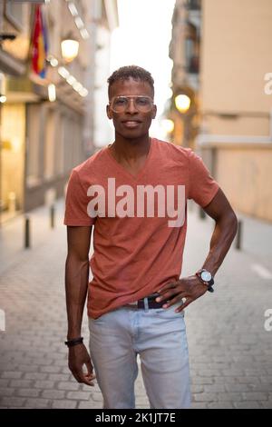 Vertikales Porträt eines modernen afrikanischen Mannes, der während des Sonnenuntergangs auf der Straße posiert Stockfoto