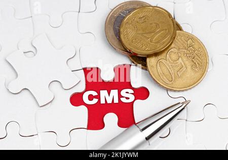 Geschäftskonzept. Auf weißen Puzzles gibt es Münzen und einen Stift, in der offenen Zelle gibt es eine Inschrift - CMS Stockfoto