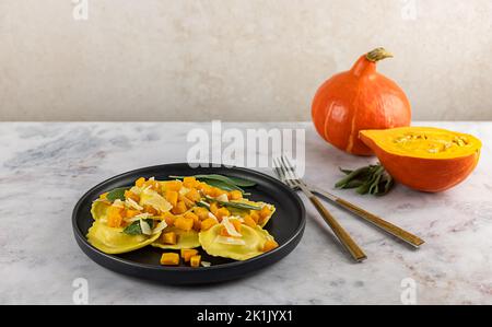 Saisonales Herbstrezept. Kürbisravioli mit Salbei, Parmesan und Olivenöl. Stockfoto