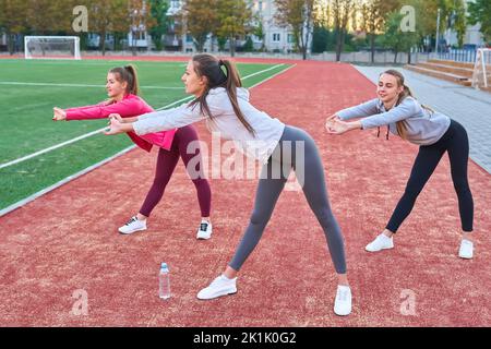 Positive Frauen Sport Übungen.. Die Gruppe der drei schöne junge Frauen, die Sport im sonnigen Tag im Park. Stockfoto