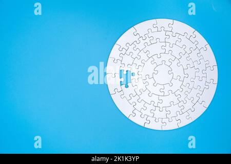 Unfertige weiße Puzzle-Stücke auf blauem Hintergrund, das letzte Stück Puzzle, Copy Space. Stockfoto