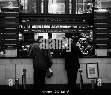 Eine Schwarz-Weiß-Aufnahme von Leuten, die an einem Bahnhof Tickets für Reisen in Union Station kaufen Stockfoto