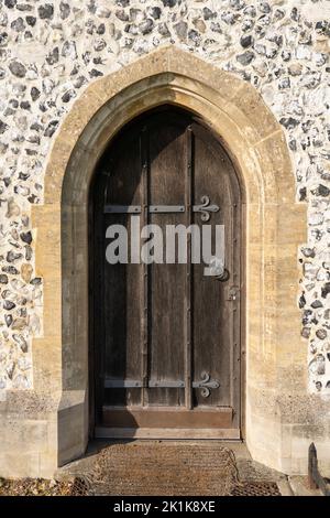 Eine alte hölzerne und eiserne Tür mit einem Steinrahmen an der St. Mary the Virgin, einer Landkirche aus dem 12.. Jahrhundert in den Stadtruinen von Silchester. Hampshire, Großbritannien Stockfoto