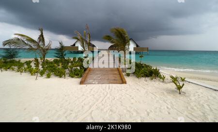 Panoramablick auf einen hölzernen Steg, der zu den Villen oder Bungalows auf einer Insel auf den Malediven führt. Stockfoto