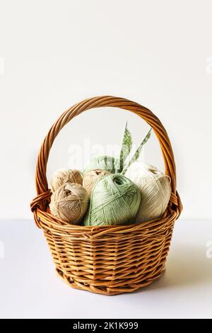 Grüne und braune Garnfäden in einem Korb zum Stricken warmer Kleidung mit Stricknadeln, Stricken Hobby Stockfoto