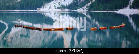 Atemberaubende Aussicht auf den Pragser See (Lago di Prags) mit einigen Holzbooten und wunderschönen Bergen, die sich im Wasser spiegeln. Stockfoto