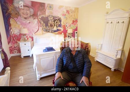 Deutschland. 19. September 2022. 19. September 2022, Rheinland-Pfalz, Vettelschoß: Gary Blackburn sitzt im Queens Room seines Themenhotels „Little Britain Inn“. Ein großformatiges Bild ziert die Wand des Themenzimmer. Foto: Thomas Frey/dpa Quelle: dpa picture Alliance/Alamy Live News Stockfoto