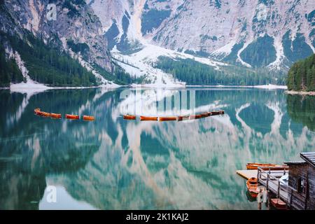 Atemberaubende Aussicht auf den Pragser See (Lago di Prags) mit einigen Holzbooten und wunderschönen Bergen, die sich im Wasser spiegeln. Stockfoto