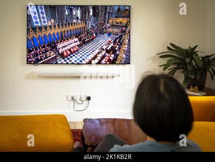 Billingshurst, Großbritannien. 19. September 2022. Eine Frau sieht sich in ihrem Haus eine Live-Übertragung der staatlichen Beerdigung von Königin Elizabeth II. In Billingshurst, West Sussex, Großbritannien, an. 19. September 2022. Menschen aus ganz Großbritannien und der ganzen Welt schauten sich das offizielle Staatsbegräbnis der Königin an, die nach 70 Jahren auf dem Thron starb. Quelle: Andy Soloman/Alamy Live News Stockfoto