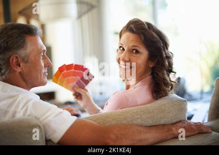 Mit einer lebendigen Farbpalette. Ein reifes Paar, das zu Hause über Farbfelder schaut, schaut zusammen. Stockfoto