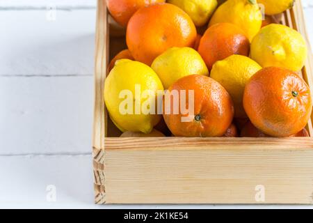 Zitrus. Schachtel mit frischen Zitrusfrüchten und Orange. Orangen und Zitronen in Holzkiste auf weiß mit Kopierraum. Erntekonzept. Stockfoto