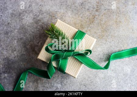 Ansicht von oben auf eine rustikale Geschenkbox mit einem Band gebunden und mit einem Tannenzweig dekoriert Stockfoto