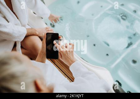 Draufsicht auf das ältere Paar, das mit dem Smartphone eine Badewanne im Freien gestellt hat. Stockfoto