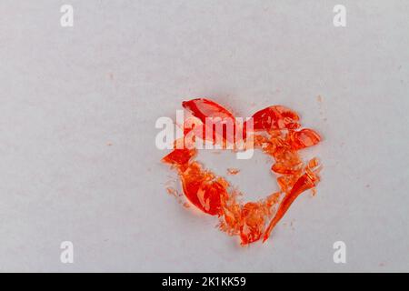 Draufsicht auf gebrochenen herzförmigen Lollipop auf weißer Oberfläche. Draufsicht flach liegend. Stockfoto