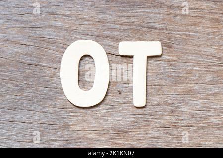 Buchstabe im Wort OT (Abkürzung für Überstunden) auf Holzhintergrund Stockfoto